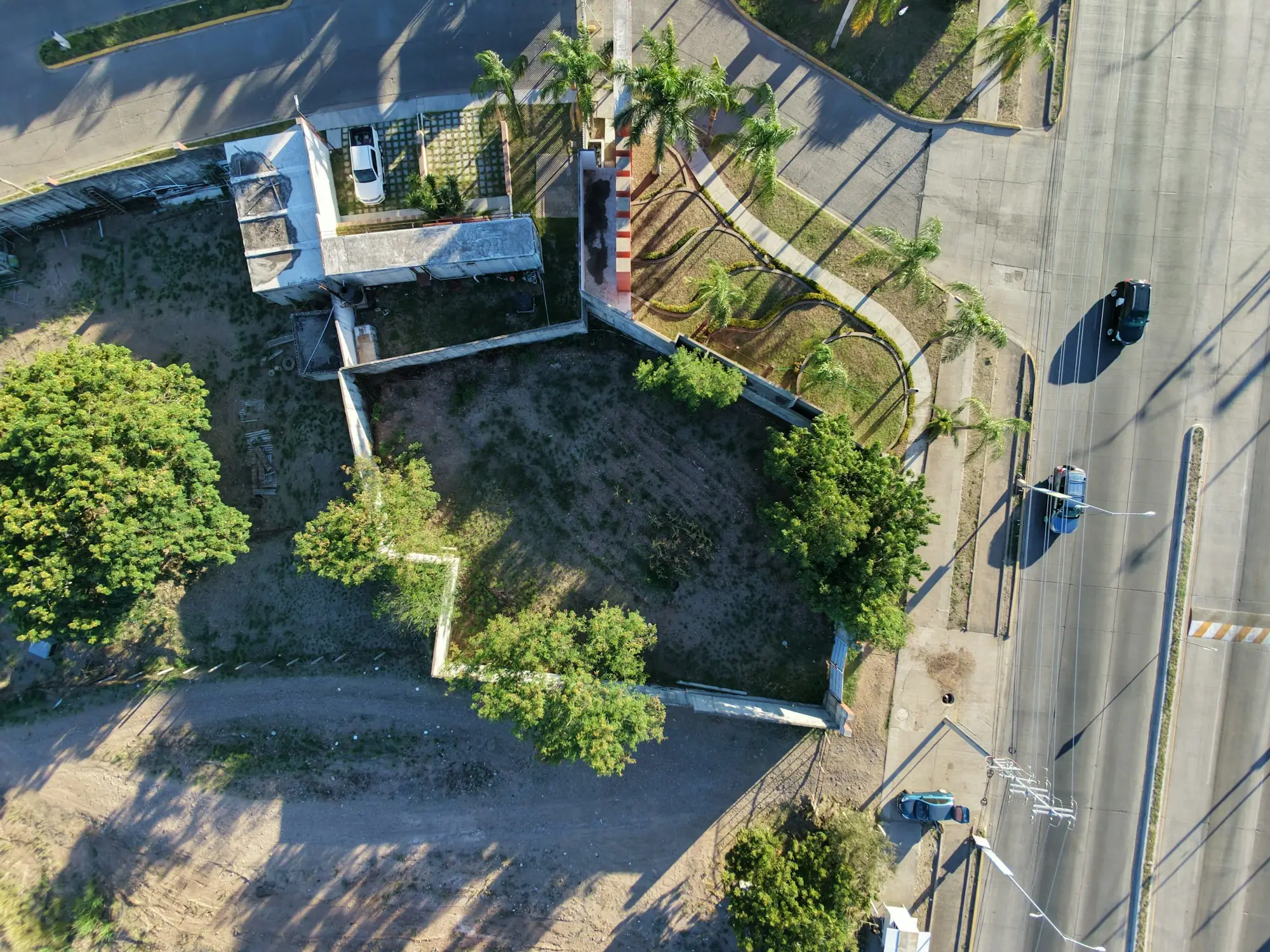 Aerial view of a vacant lot with trees beside a street