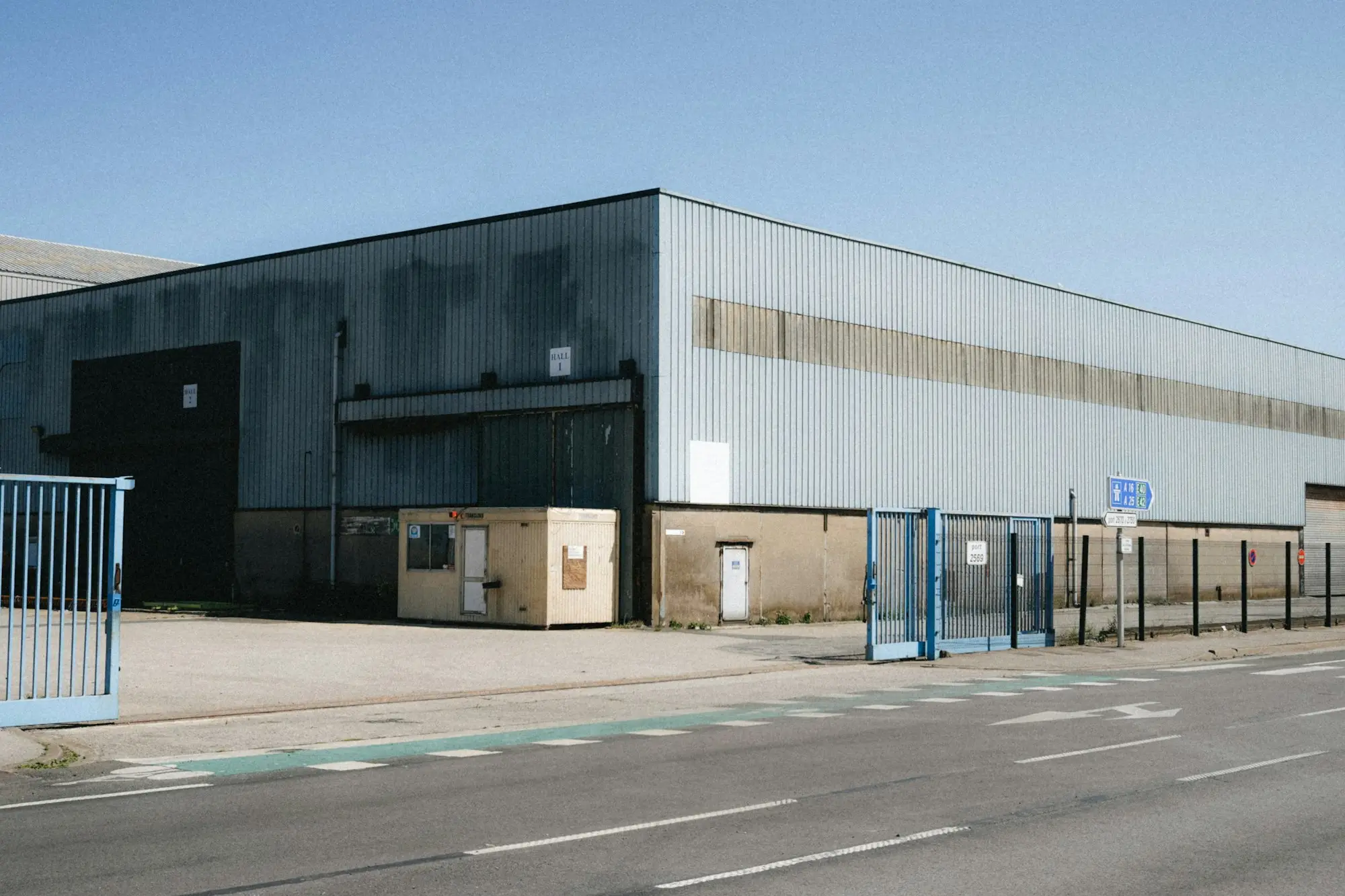 Large industrial warehouse with blue gates beside the road