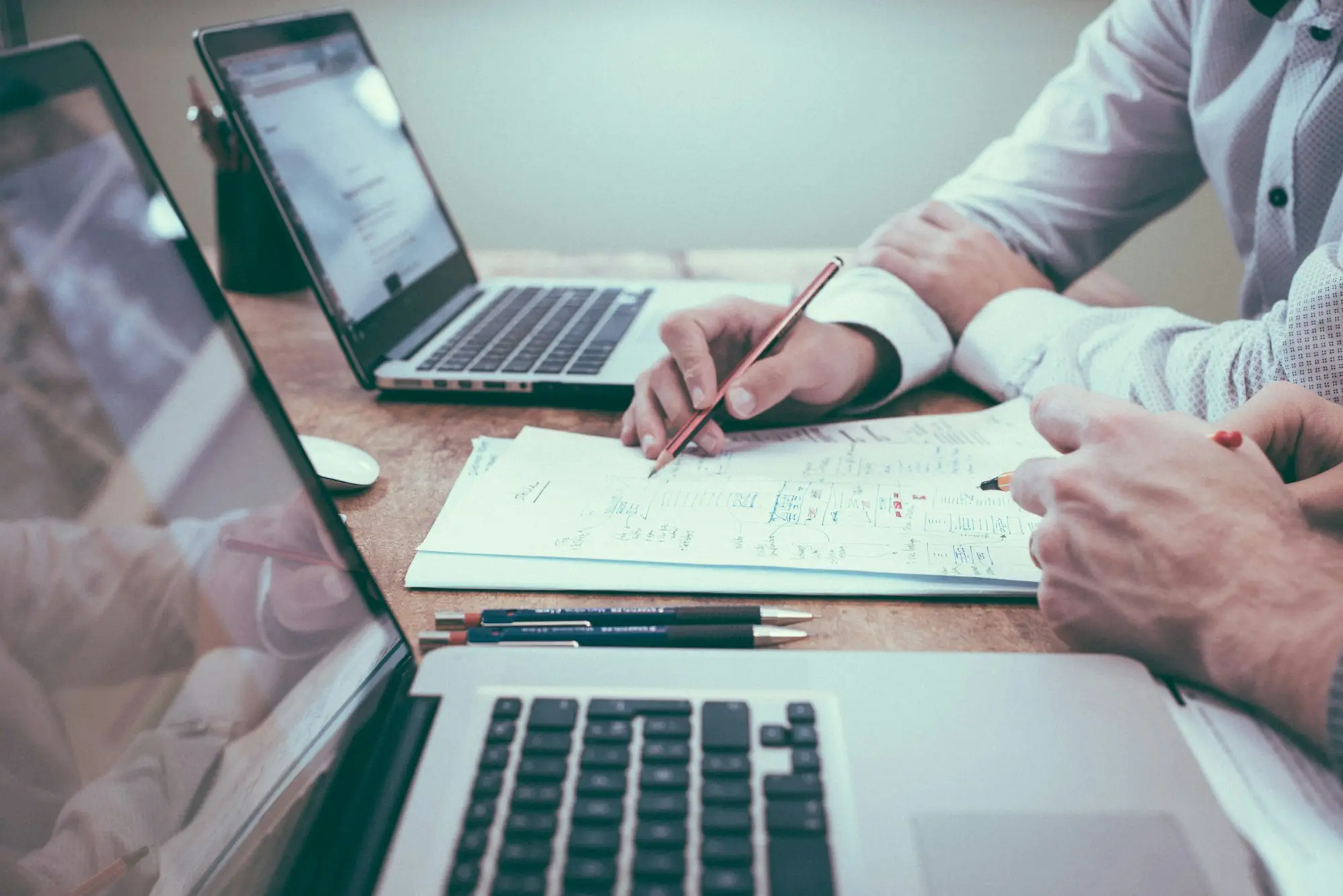Business owner holding a pencil beside a laptop while planning finance